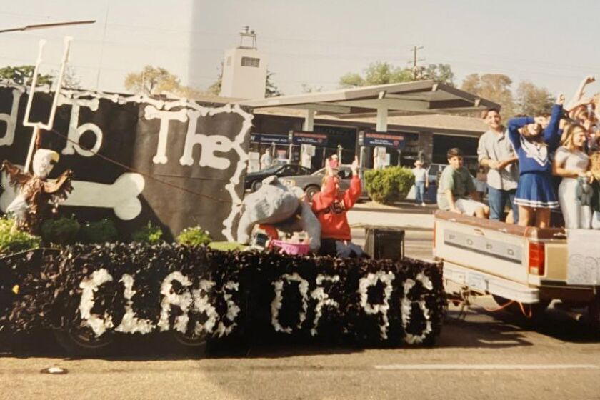 Students from the Class of 1996 wave to parade spectators as they display a “Bad to the Bone” float.