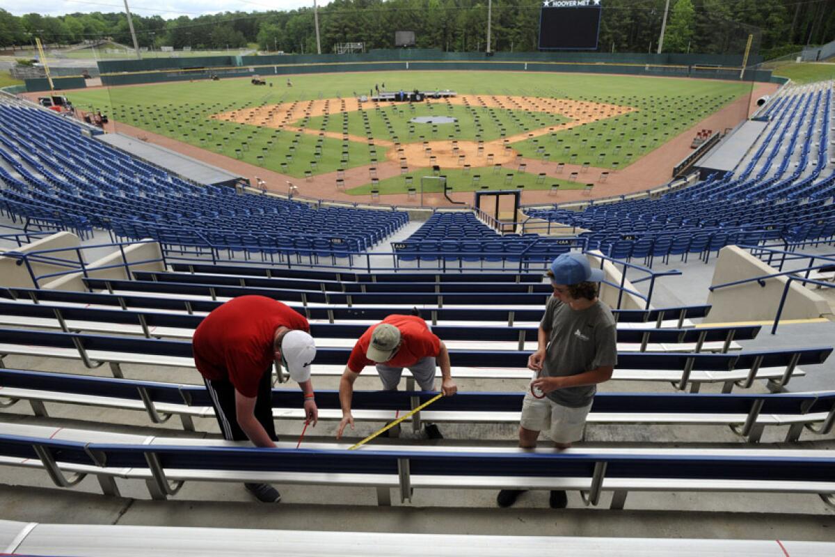 Workers block off seats with red tape May 19 as they prepare for a large high school graduation ceremony in Hoover, Ala.