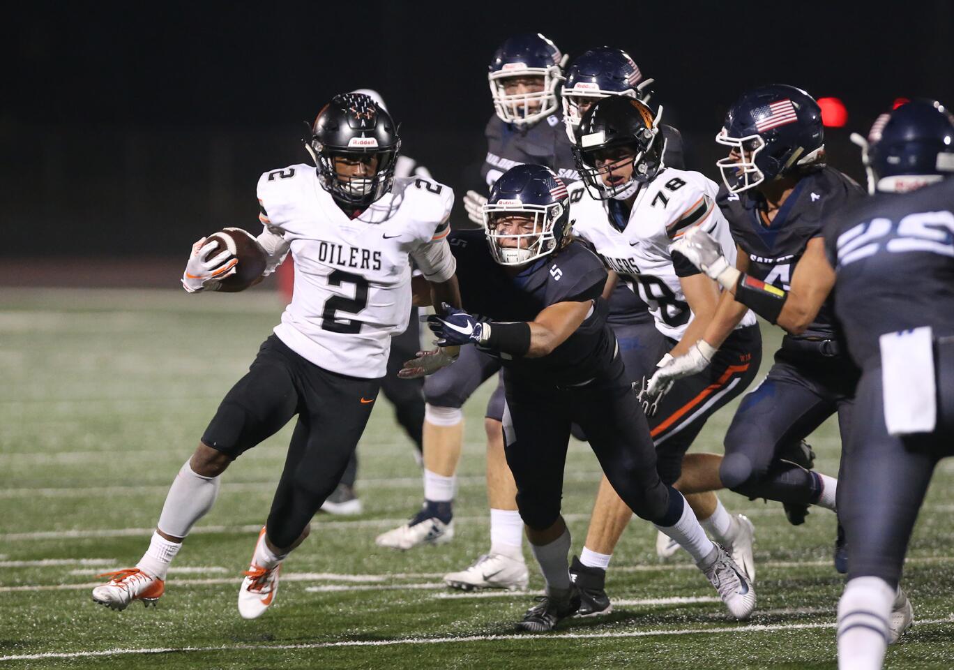 Huntington Beach High's Arick McLawer runs around end as Newport Harbor High defenders give chase during Sunset League football on Friday at Newport Harbor.