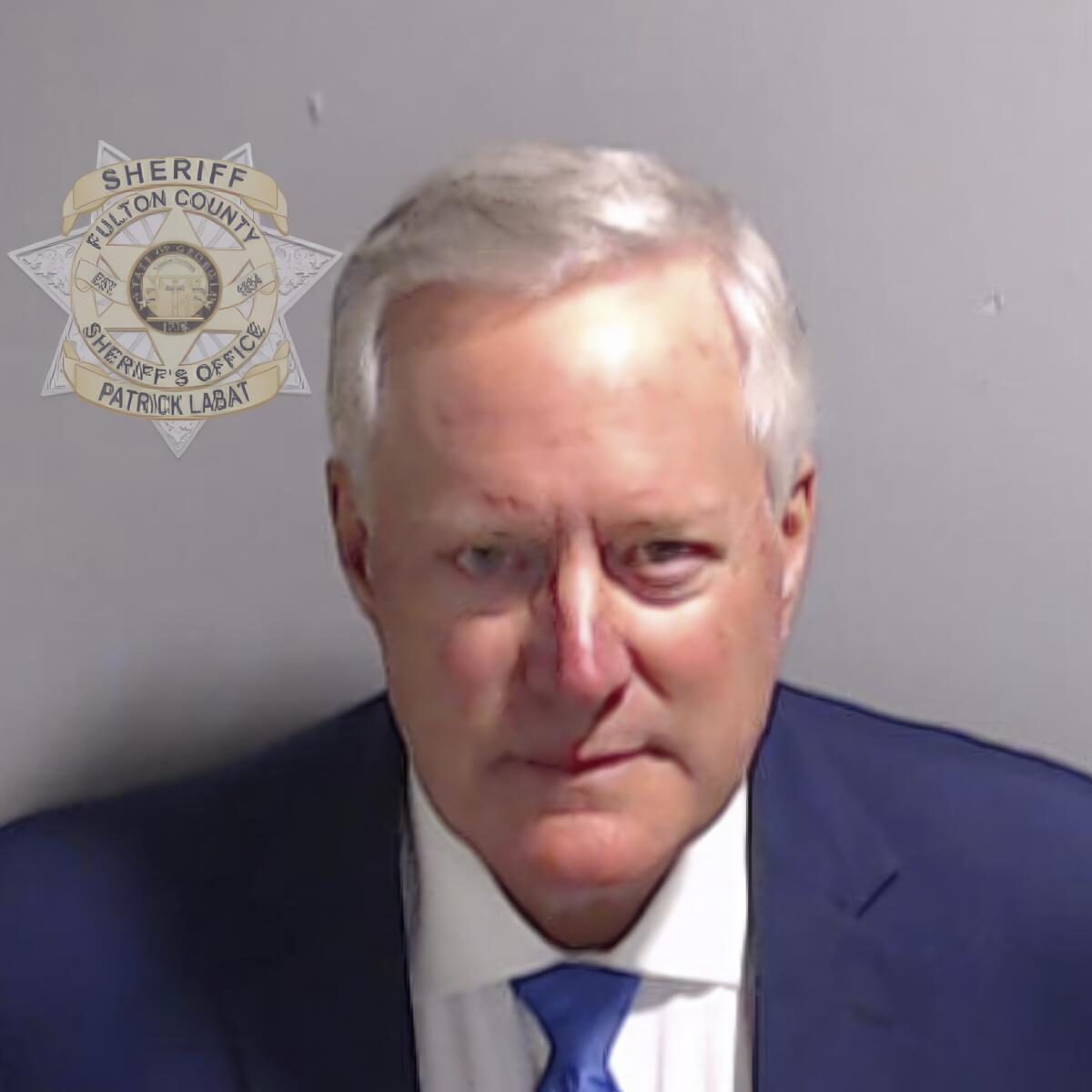 Booking photo of Mark Meadows in a blue suit and tie.