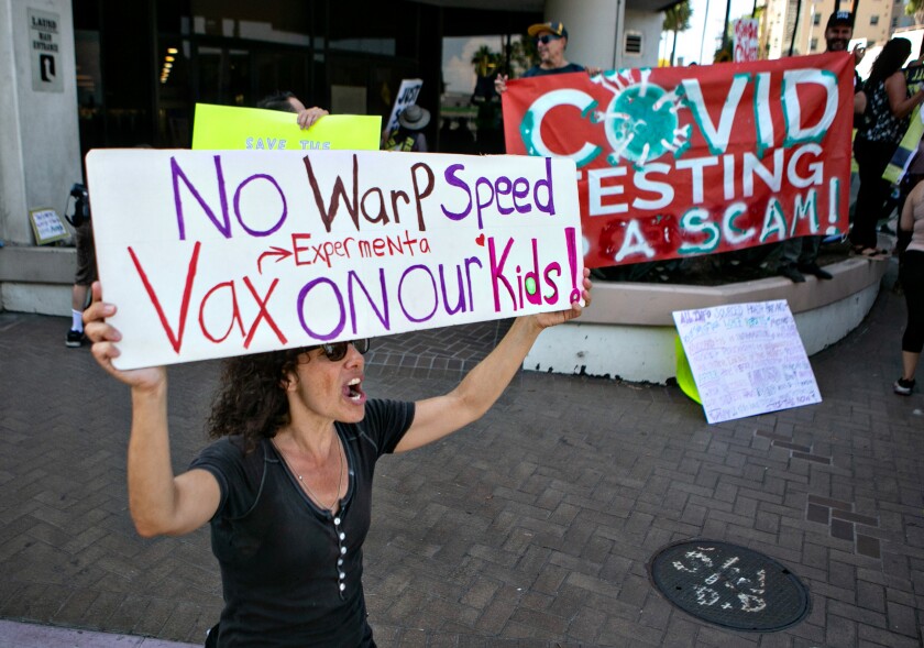A woman holds a sign that reads, "No warp speed experimental vax on our kids!"
