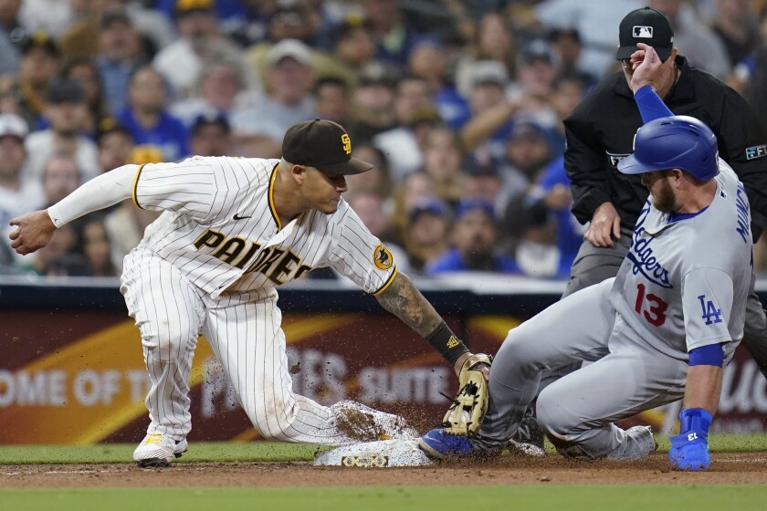 The Dodgers' Max Muncy advances to third on a wild pitch as Padres third baseman Manny Machado is late with the tag