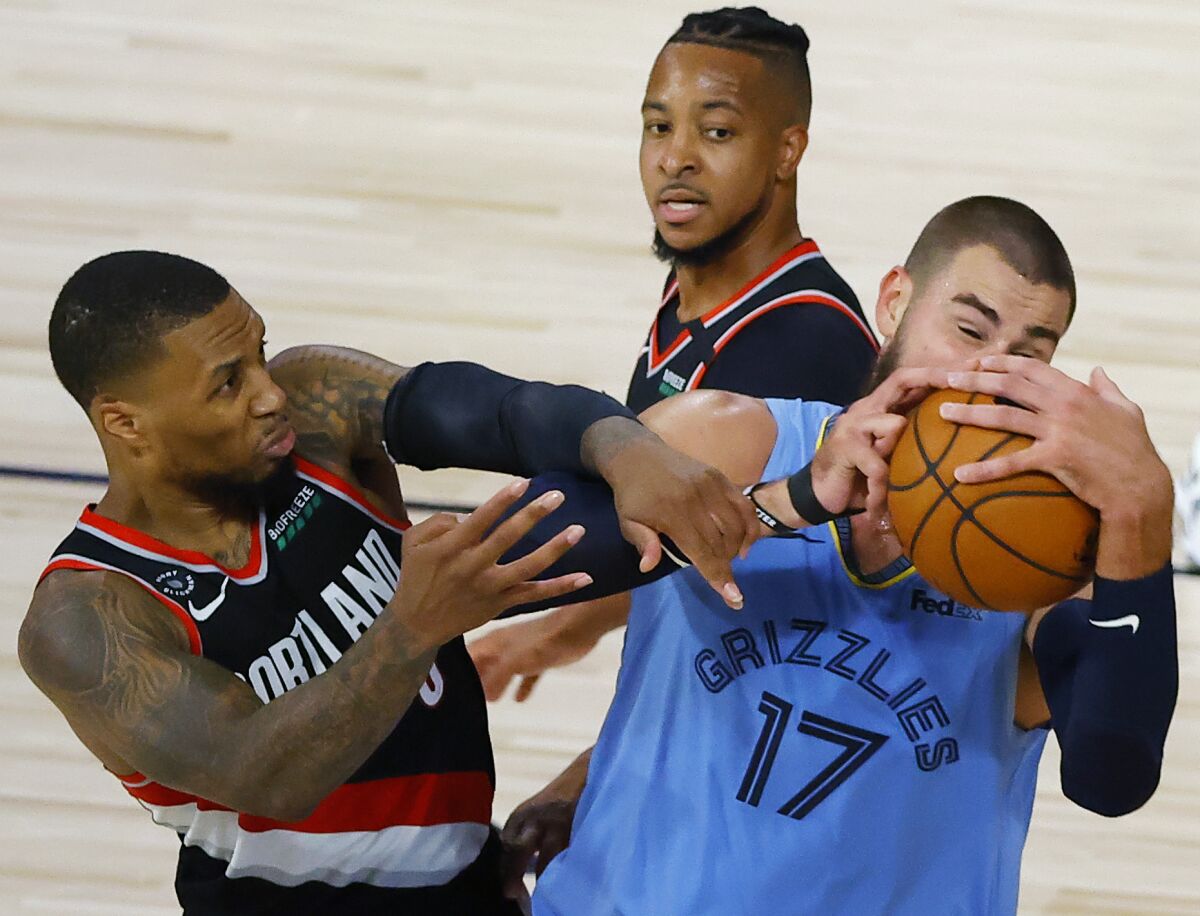 The Memphis Grizzlies' Jonas Valanciunas and Portland Trail Blazers' Damian Lillard tangle.