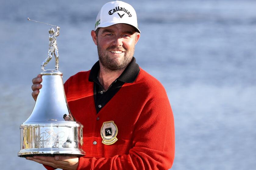 Marc Leishman poses with the winner's trophy and the new ceremonial red sweater after winning the Arnold Palmer Invitational on Sunday.