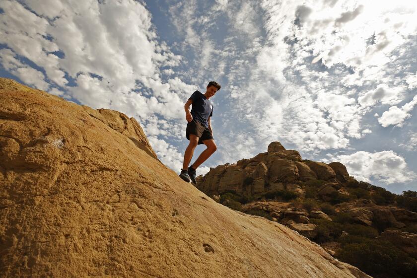 CHATSWORTH, CA - JULY 08: Under cloudy skies Josh Puchalski, 20, with a couple of fellow UCLA student friends scrambles down a rock face while practicing their Bouldering skills at Stoney Point Park in Chatsworth before temperatures began to soar Thursday morning as a new heatwave is predicted to bring dangerously hot weather to California's inland regions this week, with relentlessly high temperatures that continue to torment the west coast. Stoney Point Park on Thursday, July 8, 2021 in Chatsworth, CA. (Al Seib / Los Angeles Times).