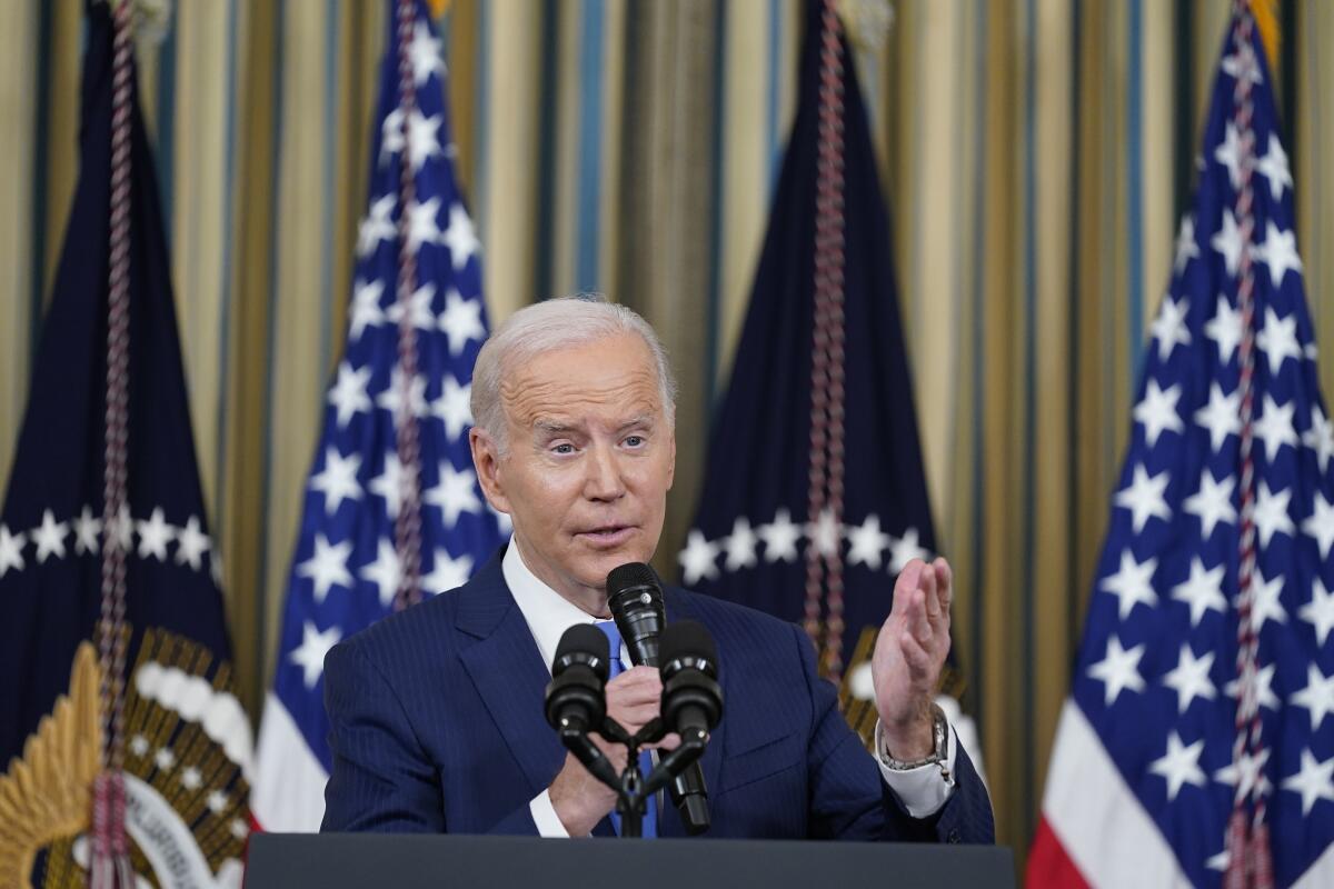 President Biden speaks at a lectern with flags behind him.