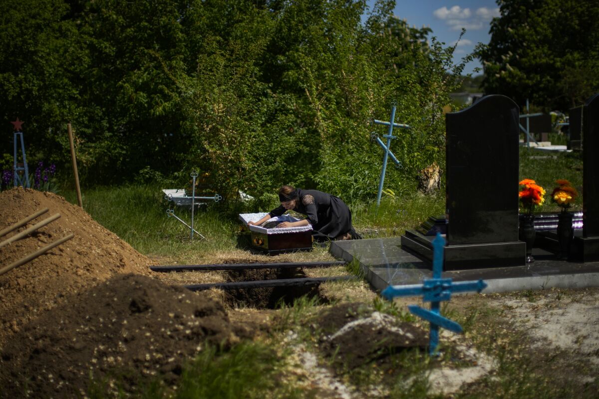 Iuliia Loseva cries over the coffin of her husband Volodymyr Losev, 38, during his funeral at a cemetery in Zorya Truda, Odesa region, Ukraine, Monday, May 16, 2022. Volodymyr Losev, a Ukrainian volunteer soldier, was killed on May 7 when the military vehicle he was driving ran over a mine in eastern Ukraine. (AP Photo/Francisco Seco)