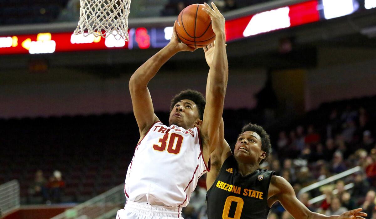 The Trojans’ Elijah Stewart dodges defensive pressure from the Sun Devils’ Tra Holder and goes up for score Sunday night. Stewart made seven of USC’s 14 three-pointers and finished with 29 points.
