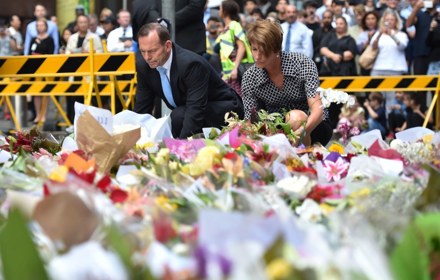 Prime Minister Tony Abbott and his wife, Margaret, place wreaths Dec. 16 at a makeshift memorial near the scene of a fatal hostage siege in the heart of Sydney's financial district.