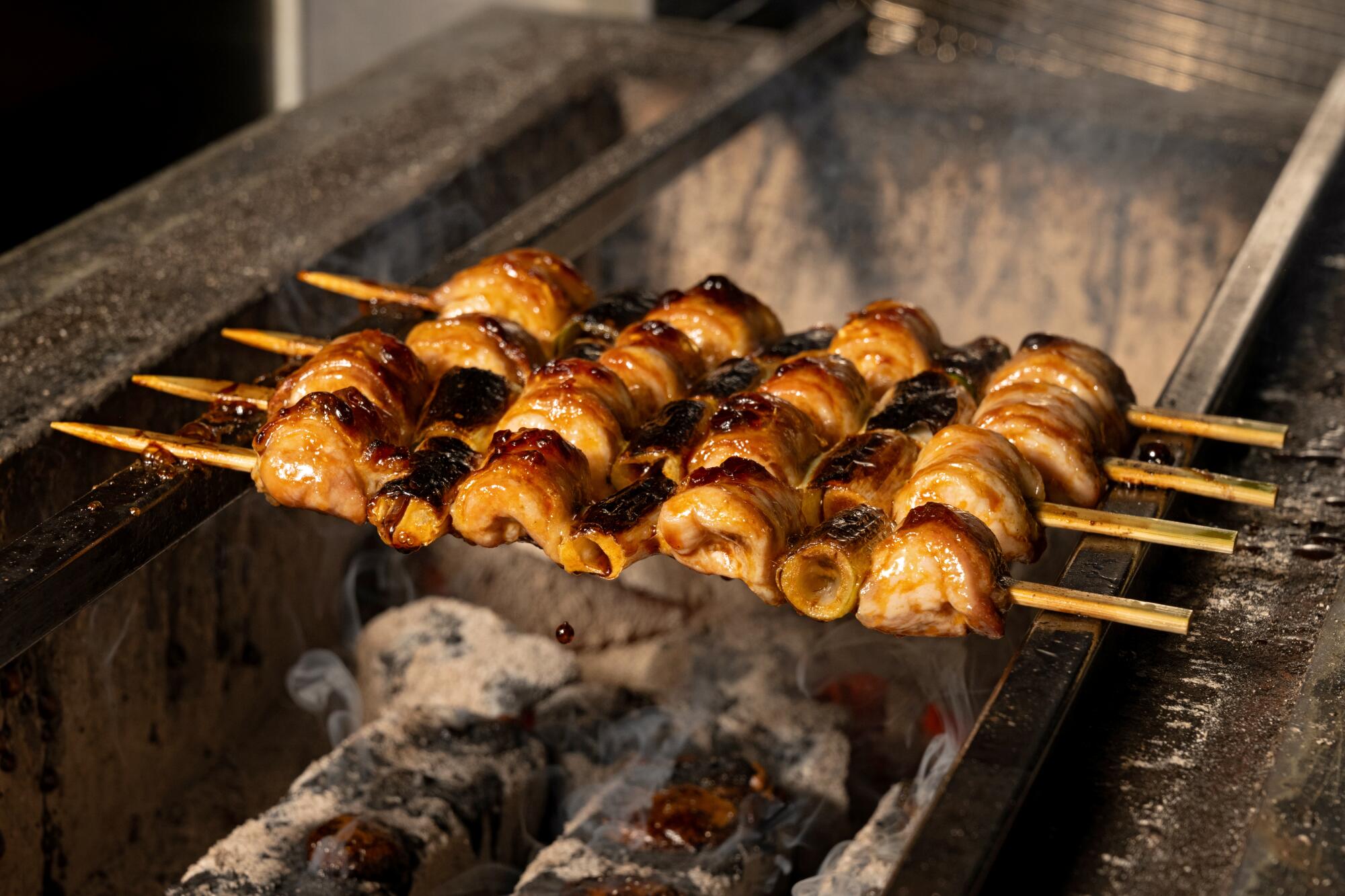 Pieces of chicken on skewers over a charcoal grill