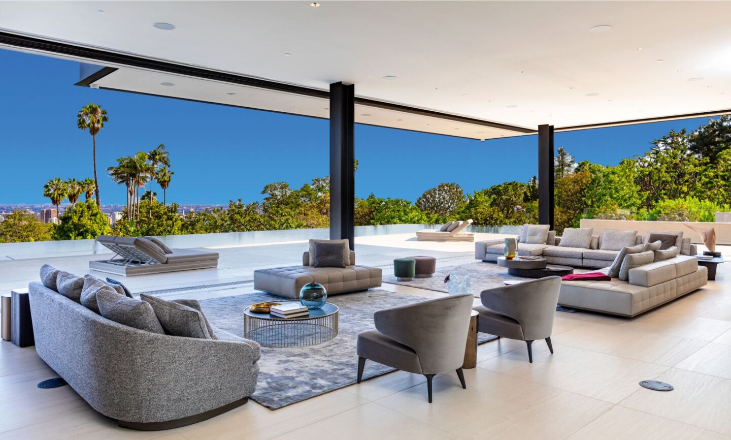 The indoor-outdoor covered, furnished living room overlooks trees and sky.