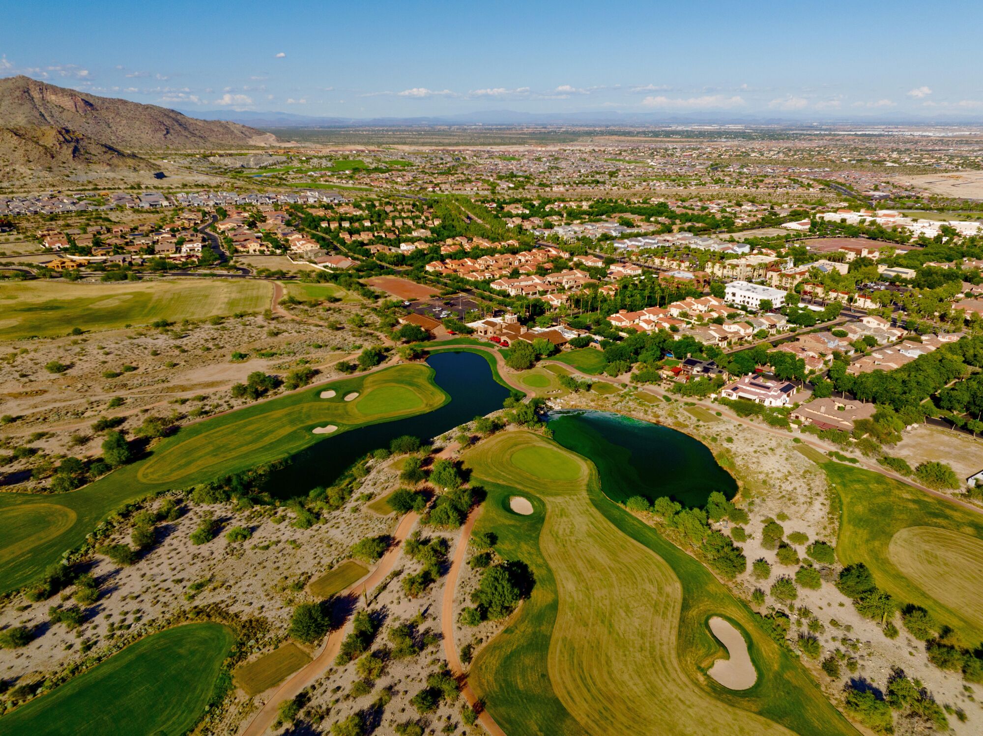 Overhead view of a green golf course surrounded by suburbs