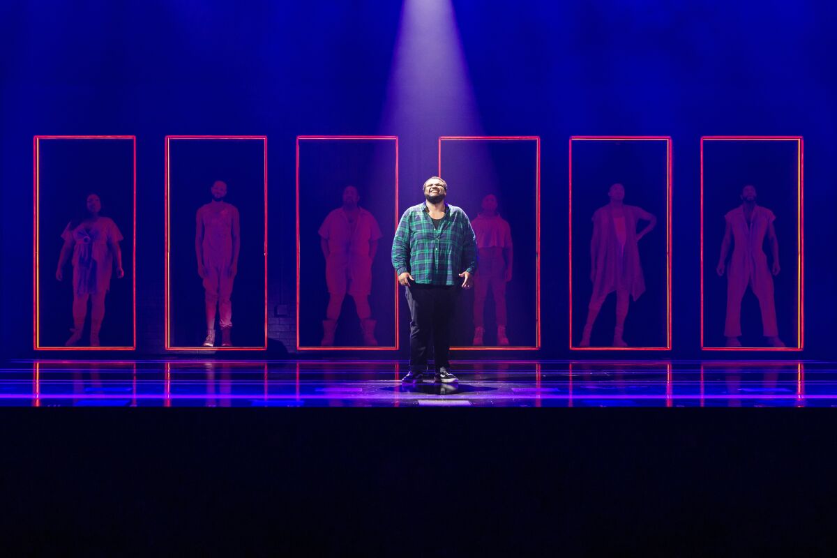Jaquel Spivey is shown standing on a stage before a series of red neon rectangles