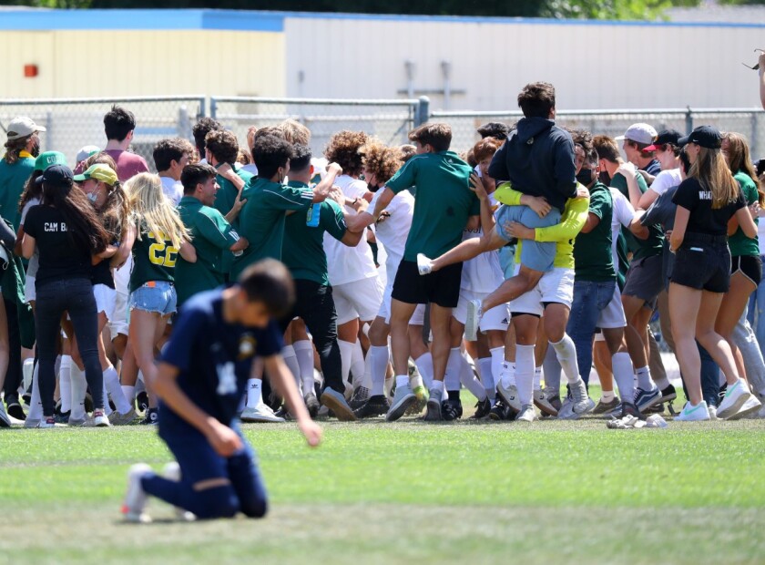 A Birmingham player falls to his knees while Mira Costa players celebrate the win.