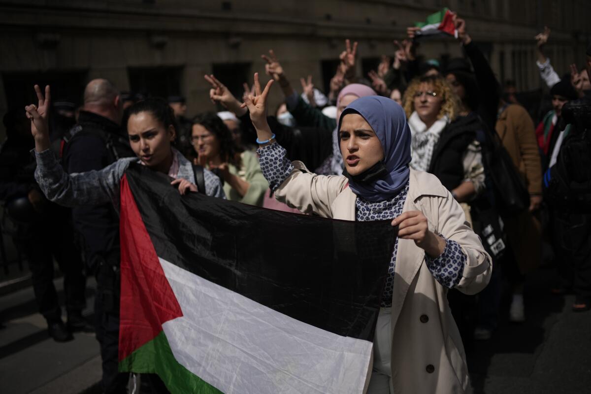 Led by two women holding a Palestinian flag, students march making peace signs with their hands