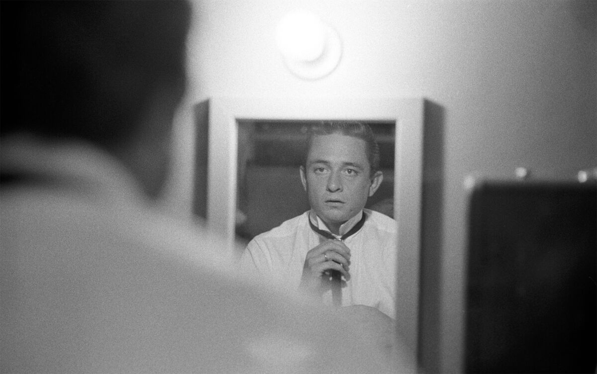 Johnny Cash adjusts his tie in a mirror in a photo from the documentary 'The Gift: The Journey of Johnny Cash'