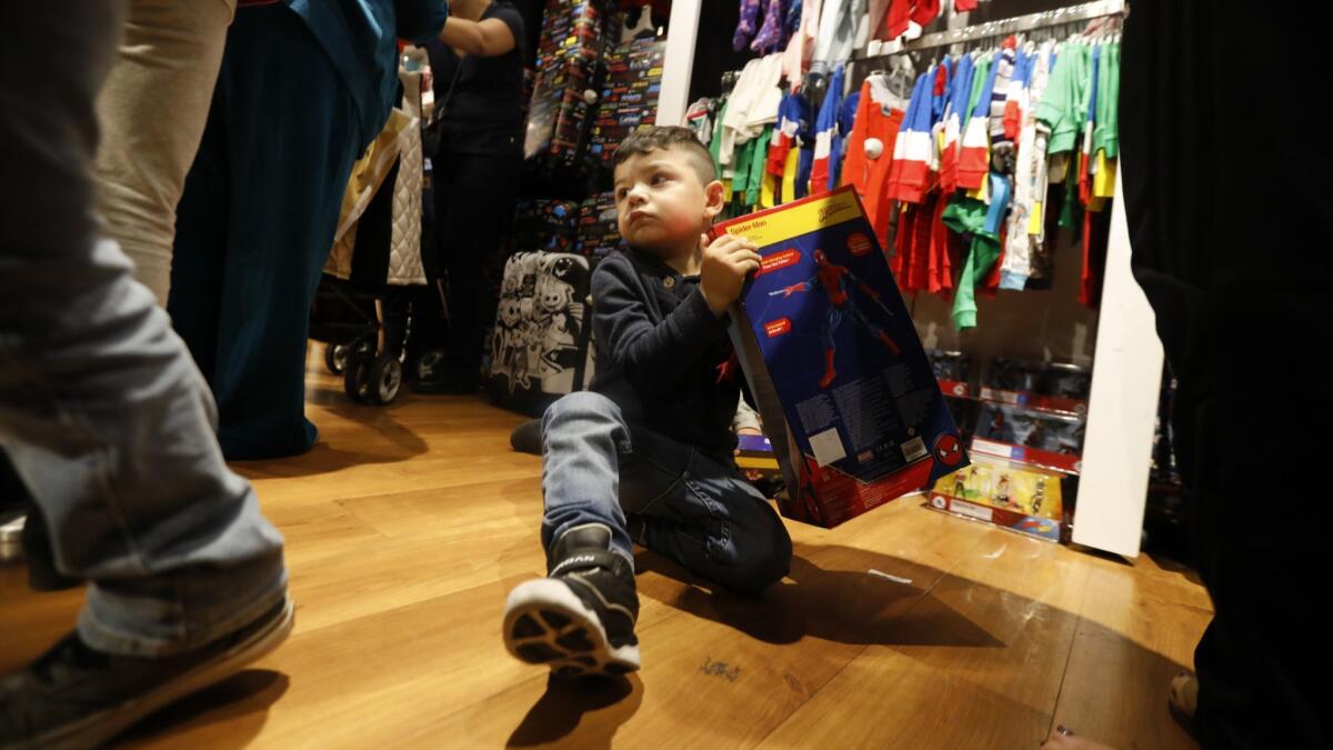 As shoppers look for bargains, Adrian Leal, 3, sits on the floor in line with his new Spiderman at the Disney Store at the Citadel.