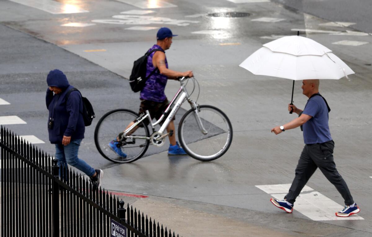 Pedestrians make their way through an afternoon rain in downtown Los Angeles on June 3, 2025.