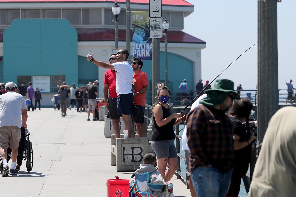 Visitors stand on a bench for an elevated picture at Huntington Beach Pier.