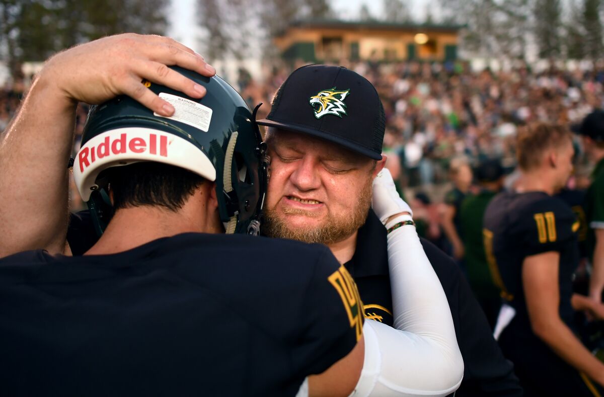 Paradise assistant football coach Andy Hopper cries as he hugs running back Tyler Harrison before the game.