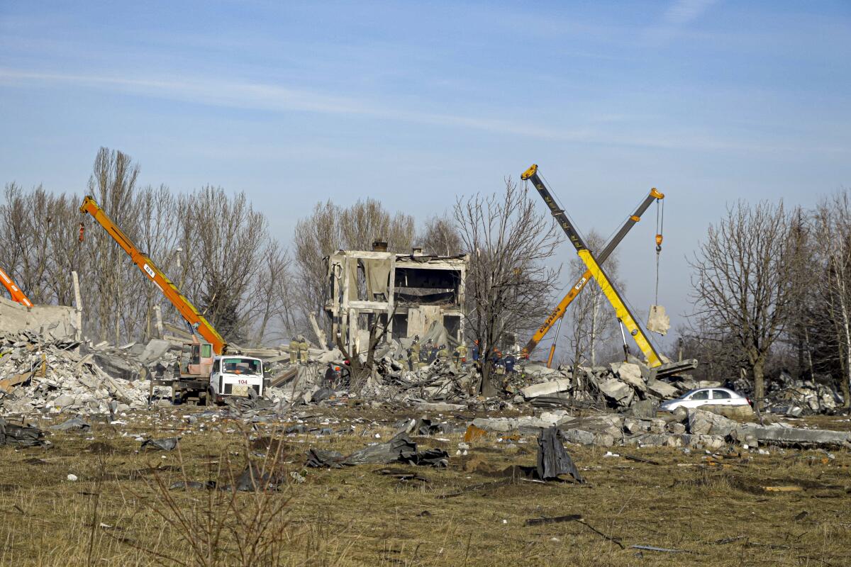 Workers and cranes clean rubble after a rocket strike in Makiivka, Ukraine.