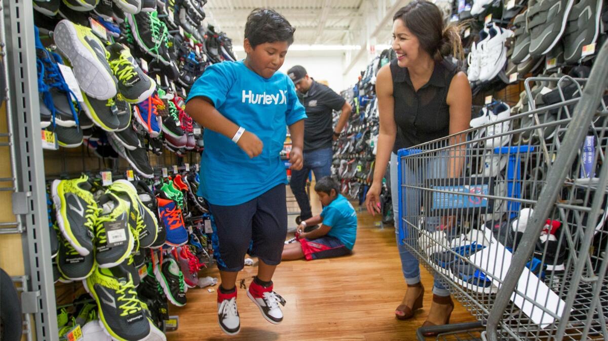 Carlos Cardoso, 9, jumps to test a pair of basketball shoes as volunteer Celina Hernandez watches. The Huntington Beach Auto Dealers Assn. and the Boys and Girls Clubs of Huntington Valley teamed up to provide 50 children from the club's Oak View branch with a shopping spree.