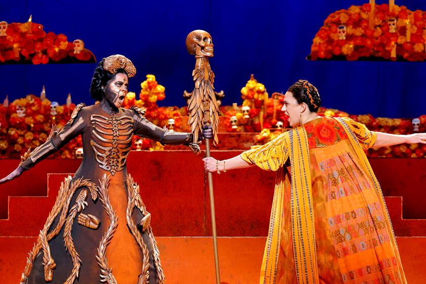 Performers costumed as a Day of the Dead calavera and Frida Kahlo perform a dramatic scene in an opera on stage