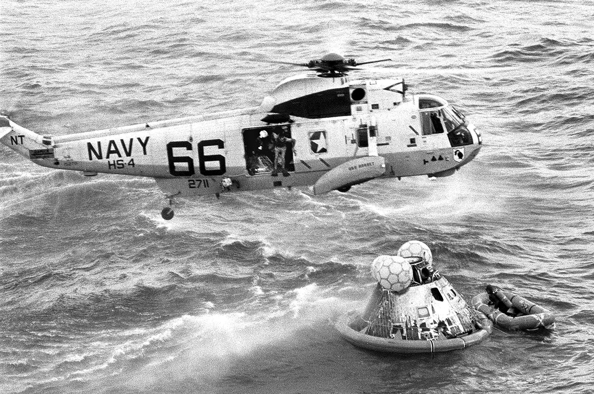 A helicopter hovers over the Apollo 11 capsule 