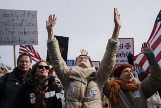 WASHINGTON, DC - JANUARY 23: Jenny Burrill, of Brooklyn, NY raises her hands in the air as people cheer after singing the National Anthem as they participate in a Defeat the Mandates Rally, on National Mall on Sunday, Jan. 23, 2022 in Washington, DC. Demonstrators are protesting mask and Covid-19 vaccination mandates. (Kent Nishimura / Los Angeles Times)