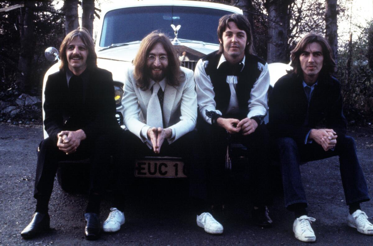 The Beatles sit in front of a Rolls Royce