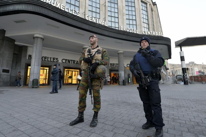 A Belgian policeman and a soldier stand guard outside the central station in Brussels on Monday.