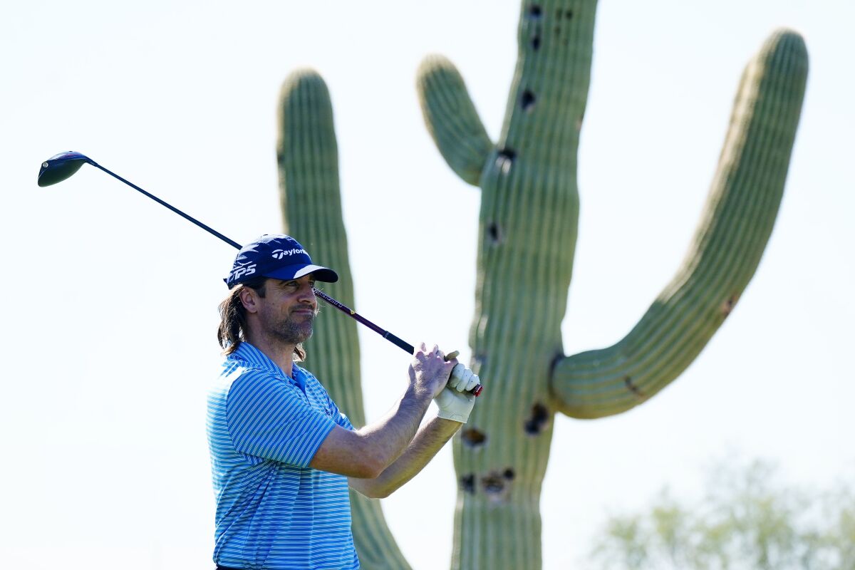 Green Bay Packers NFL football quarterback Aaron Rodgers hits his tee shot in front of a saguaro cactus at the first hole during the Pro-Am at the Phoenix Open golf tournament Wednesday, Feb. 9, 2022, in Scottsdale, Ariz. (AP Photo/Ross D. Franklin)