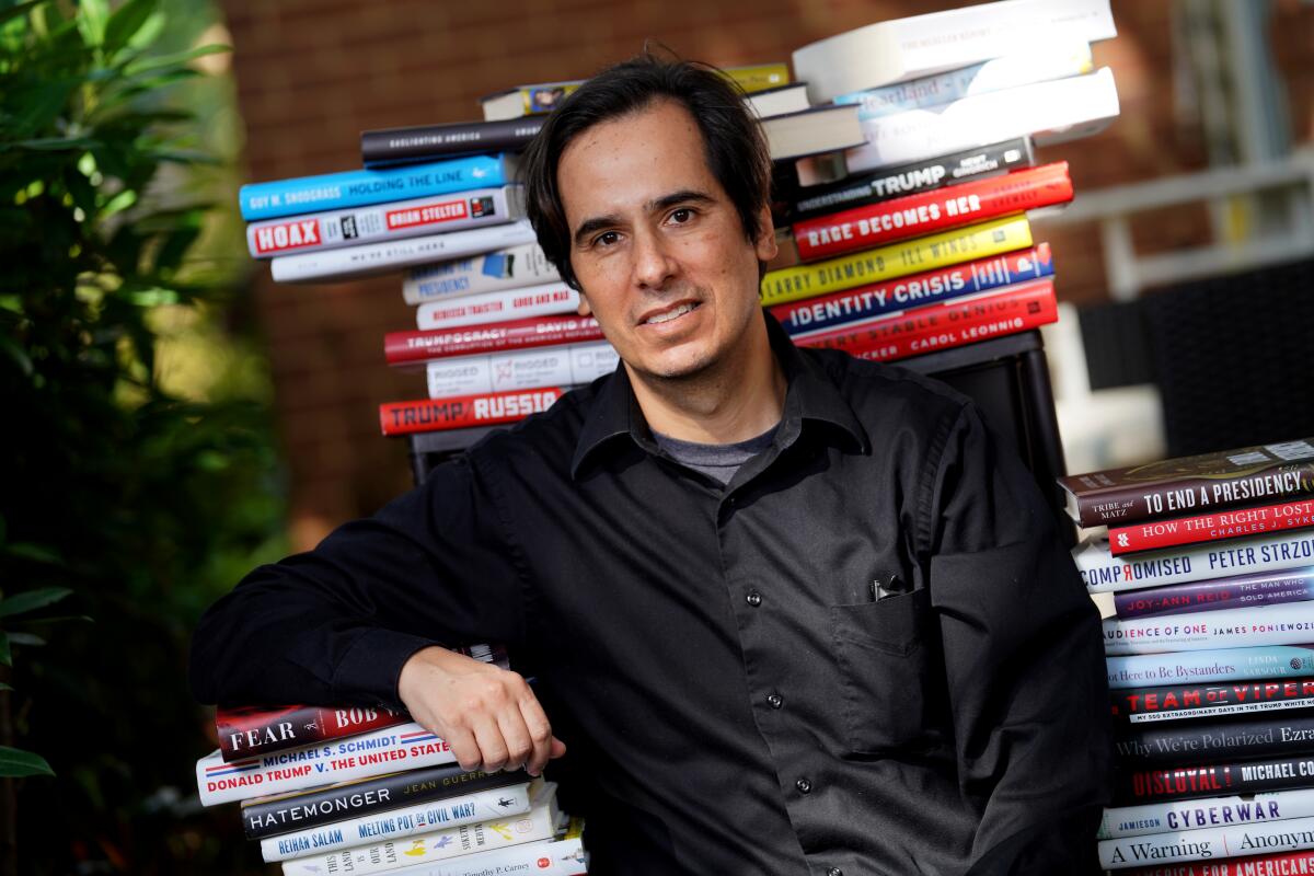 Washington Post reporter Carlos Lozada surrounded by Trump books