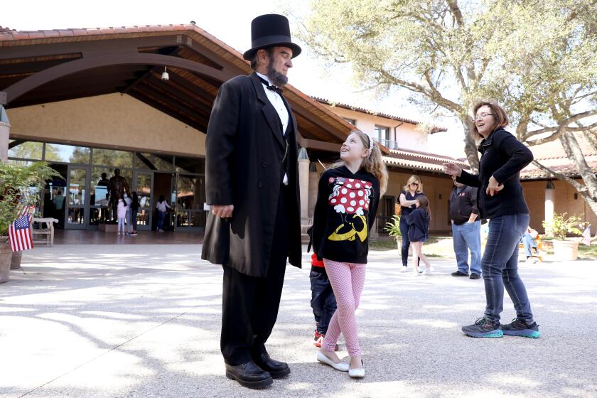 SIMI VALLEY, CA - FEBRUARY 21: J.P. Wammach, as President Abraham Lincoln, with Fiona Floyd, seven, of Simi Valley, celebrating President's Day at the Ronald Reagan Presidential Library on Monday, Feb. 21, 2022 in Simi Valley, CA. The Ronald Reagan Presidential Library is the repository of presidential records from the administration of Ronald Reagan, the 40th president of the United States, and the burial place of the president and first lady, Nancy Reagan. (Gary Coronado / Los Angeles Times)