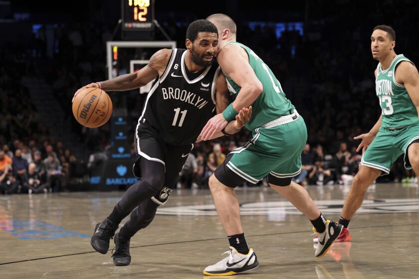 Brooklyn Nets guard Kyrie Irving (11) dribbles against Boston Celtics guard Payton Pritchard (11) as Boston Celtics guard Malcolm Brogdon (13) watches during the second half of an NBA basketball game, Sunday, Dec. 4, 2022, in New York. (AP Photo/Jessie Alcheh)