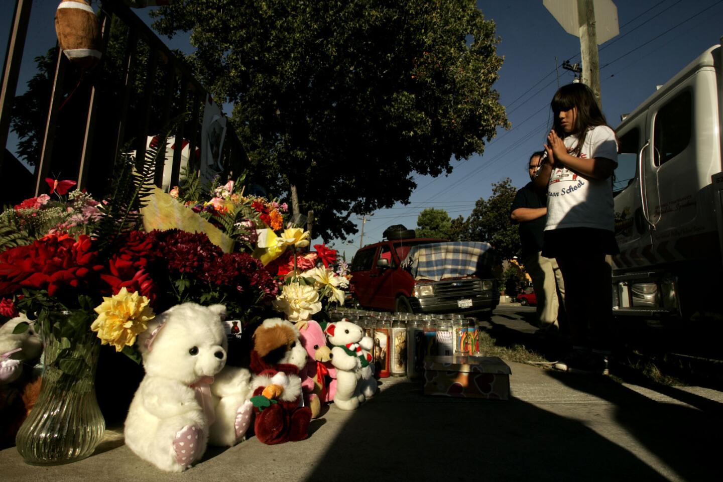 Yasmine Lizalde, 8, prays over a makeshift memorial for Dora Groce and her children Catherine, 4, and Robert, 8, who were killed in 2007 when their car was hit by a street racer at the corner of Parkway Drive and Elliott Avenue. Yasmine went to school with Robert.