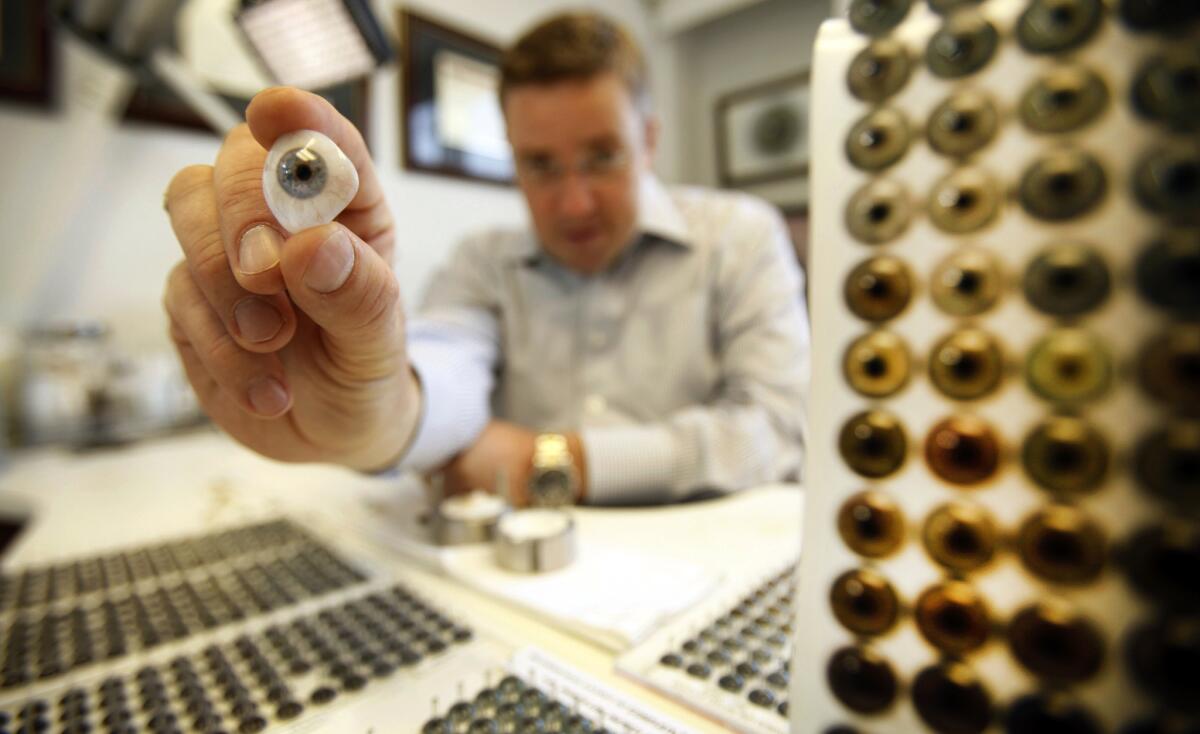 In his Tarzana office, John Stolpe, a third-generation ocularist, holds one of many prostheses he makes for patients who have lost eyes or suffered eye damage. His grandfather was on a team of Army doctors who developed fake eyes during World War II.