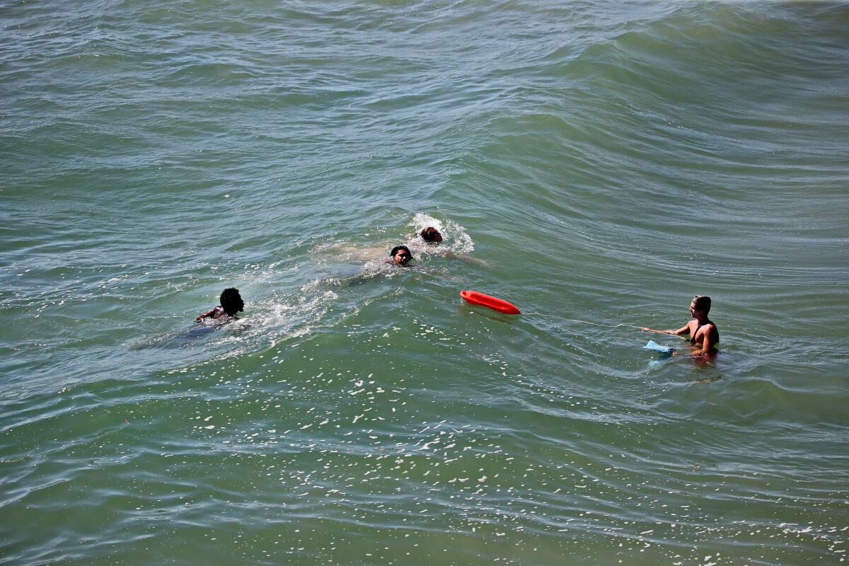 A lifeguard throws a rescue buoy toward three people who may have been stuck in a riptide in Huntington Beach in July 2020.