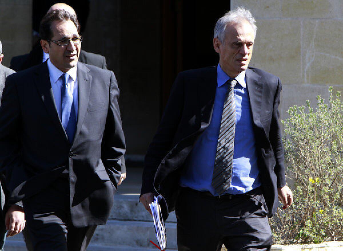 Cyprus' Financial Minister Michalis Saris, right, leaves a meeting Sunday with president Nicos Anastasiades at the presidential palace in Nicosia, Cyprus. Cyprus' parliament had postponed debate and a vote on a controversial levy on all bank deposits that the cash-strapped country's creditors demanded in exchange for a bailout.