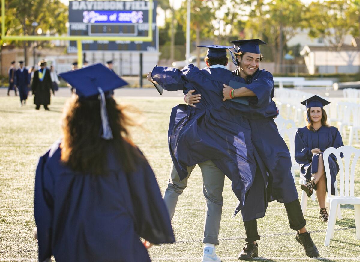 Mason Depoy, right, hugs a fellow graduate during the Newport Harbor 2021 graduation ceremony.