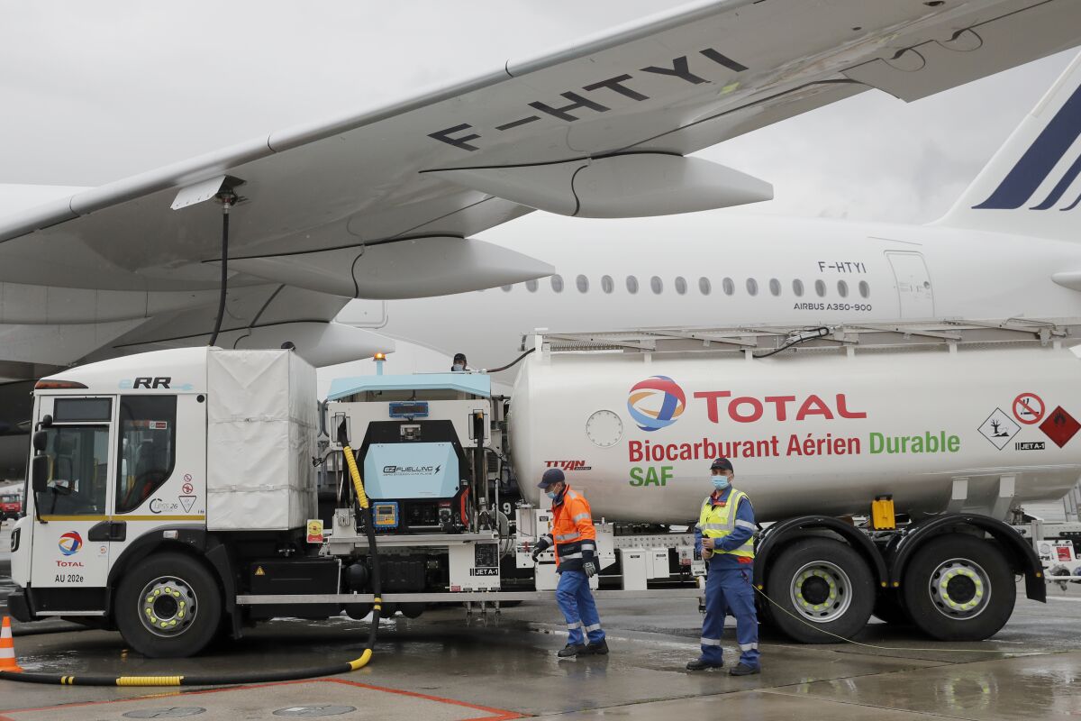 Workers refuel an Airbus A350 with sustainable aviation fuel at Roissy airport, north of Paris, Tuesday, May 18, 2021. Air France-KLM is sending into the air what it calls its first long-haul flight with sustainable aviation fuel Tuesday. The plane is said to be using petroleum mixed with a synthetic jet fuel derived from waste cooking oils. (AP Photo/Christophe Ena)
