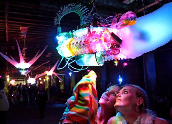 Santa Monica College students Amanda Welch, right, and her friend Lacey Mayer, take a close look at "EX-SE-08" by Shih Chieh Huang, an installation of common objects such as water bottles and plastic bags, under the Santa Monica Pier during Glow. Santa Monica hosted the Glow festival (July 17), a dusk-to-dawn celebration of temporary public art.