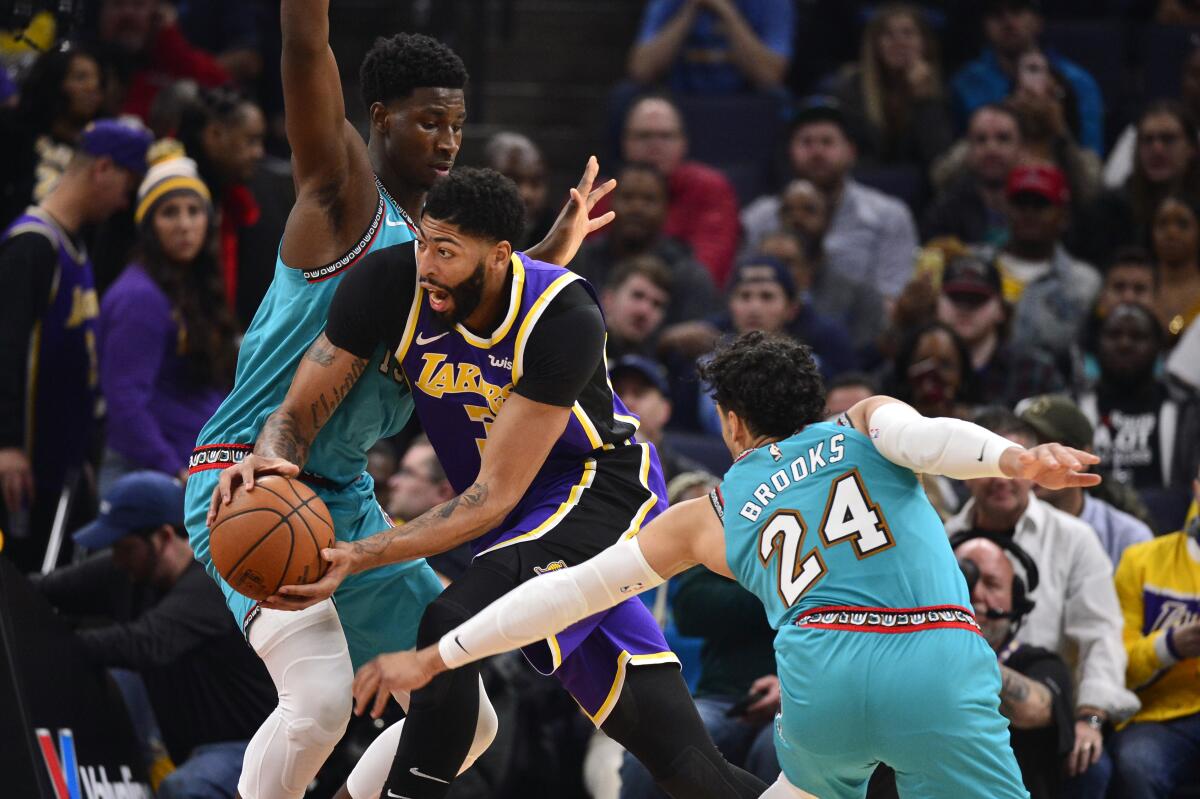 Lakers star Anthony Davis tries to split the double-team defense of Memphis forward Jaren Jackson Jr. and guard Dillon Brooks