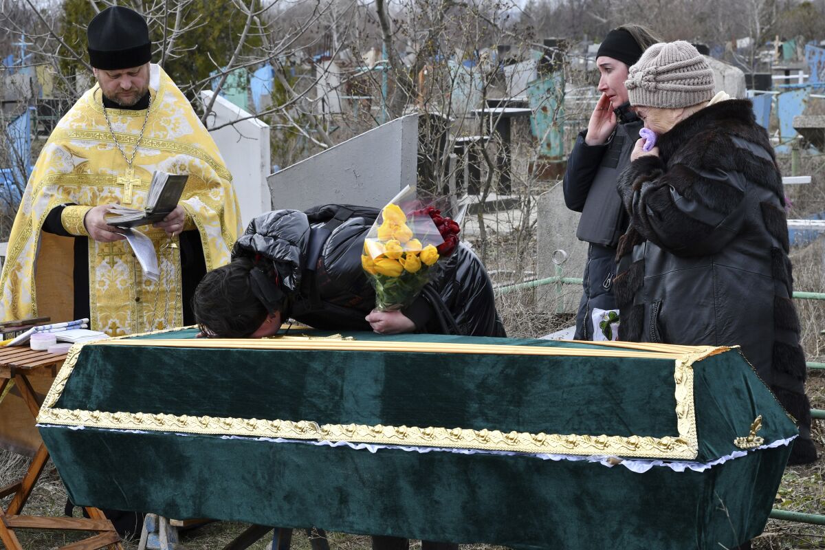 Relatives and friends stand near the coffin of Ukrainian serviceman Anatoly German during a funeral ceremony in Kramatorsk, Ukraine, Tuesday, April 5, 2022. Anatoly German was killed during fightings between Russian and Ukrainian forces near the city of Severodonetsk. He leaves a wife, daughter Adelina, 9, son Kirill, 3. (AP Photo/Andriy Andriyenko)