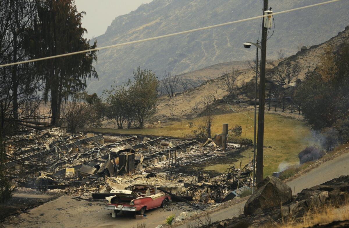 A burned structure outside Chelan, Wash., is one of dozens destroyed in a spate of Western wildfires.