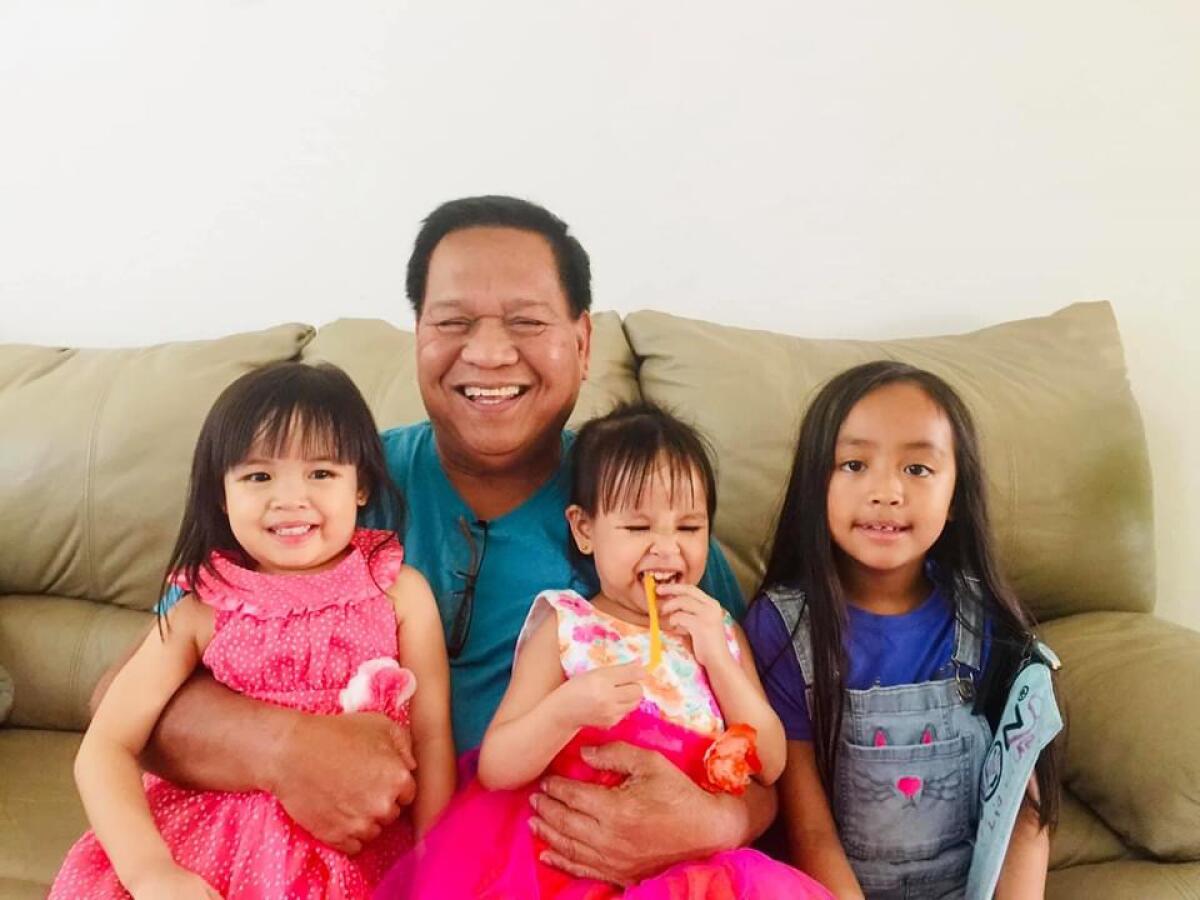 A family photo of a man and his three granddaughters on a couch