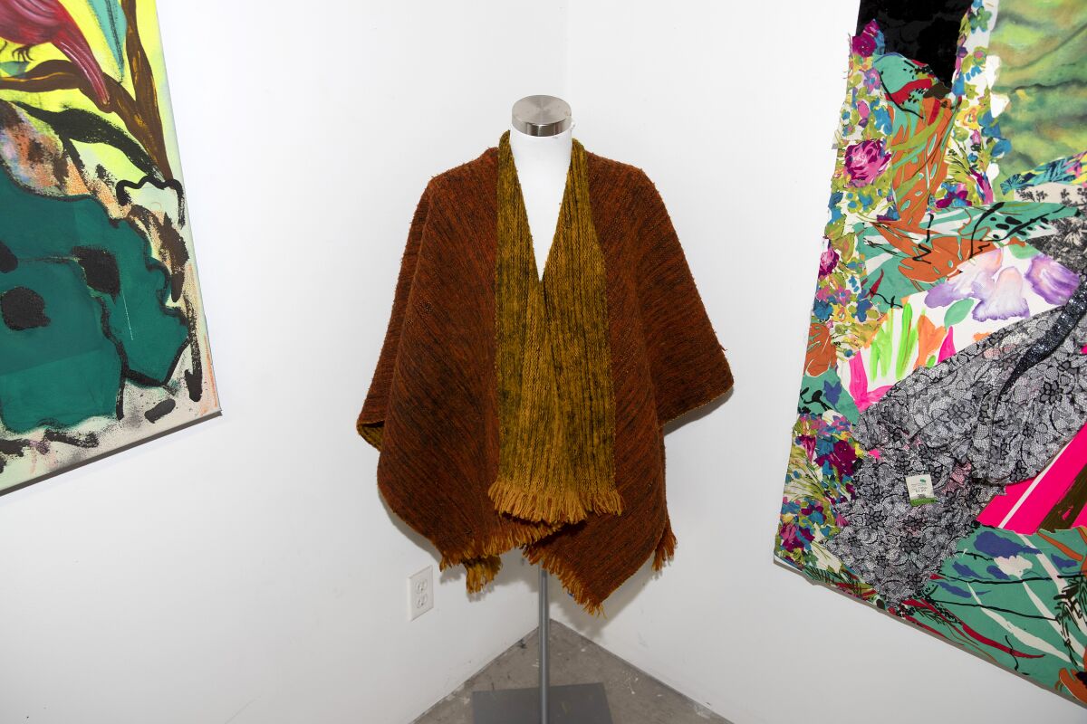 An earth-colored garment similar to a poncho on a mannequin in a corner of an art studio.