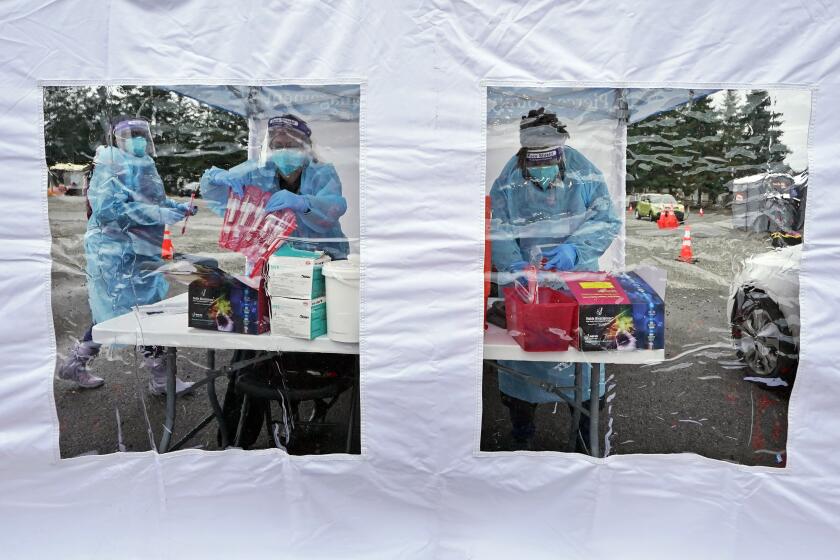 FILE - Workers at a drive-up COVID-19 testing clinic stand in a tent as they prepare PCR coronavirus tests, Jan. 4, 2022, in Puyallup, Wash., south of Seattle. Testing for COVID-19 has plummeted across the globe, dropping by 70 to 90% worldwide from the first to the second quarter of 2022, making it much tougher for scientists to track the course of the pandemic and spot new, worrisome viral mutants as they emerge and spread. (AP Photo/Ted S. Warren, File)