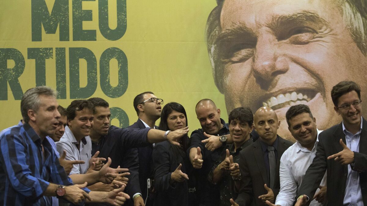 Recently elected lawmakers pose in front of an image of right-wing presidential candidate Jair Bolsonaro.