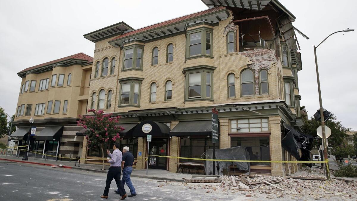 Two men walk past a quake-damaged building in Napa on Aug. 25, 2014. New research suggests the magnitude 6.0 earthquake that rocked California wine country may have been caused by an expansion of Earth's crust due to seasonally receding groundwater.